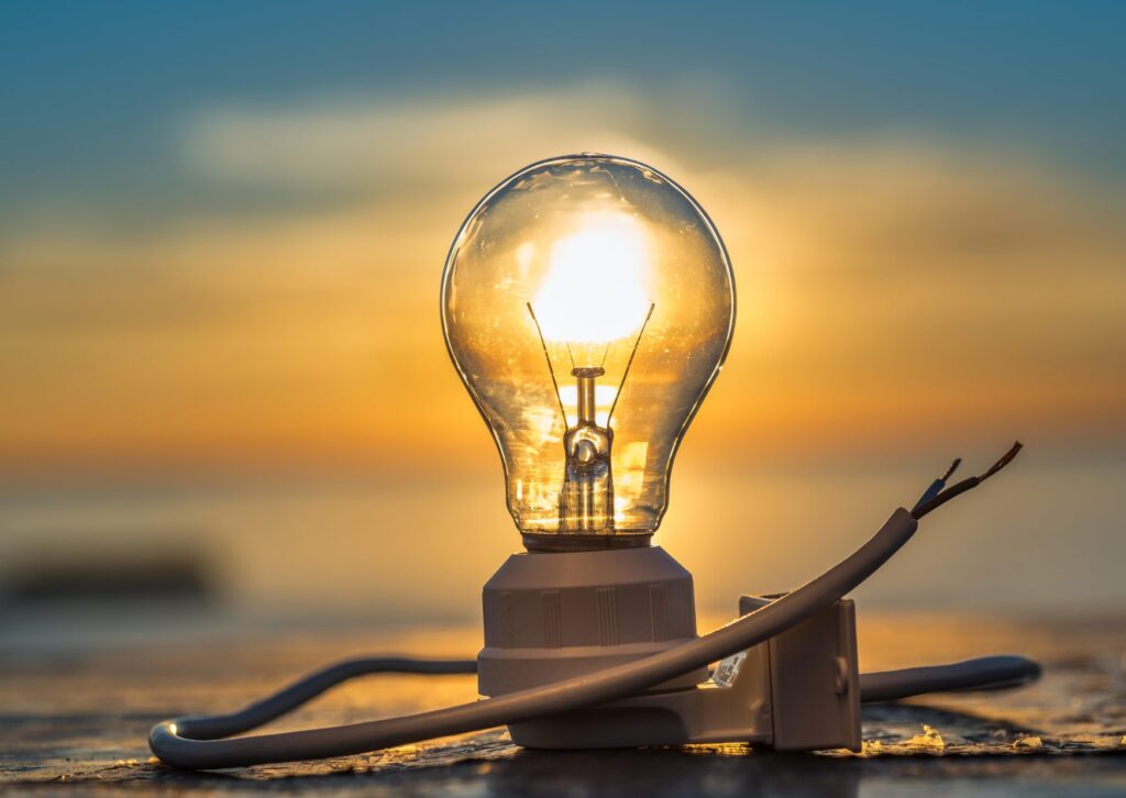 A lightbulb illuminated by the sun in the background. In this article, we elucidate which solar pv grants are available in Ireland.