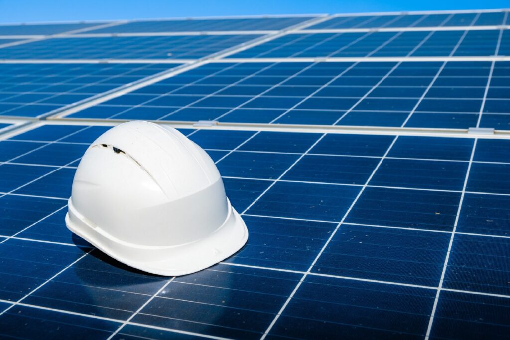 A hard hat on some solar panels, referring to the utility of solar PV for businesses now.