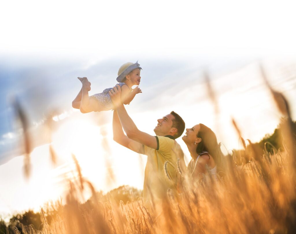 Sustainable solar Investments for the future. A couple playing with their baby in a field on a sunny day, ideal for generating solar power.
