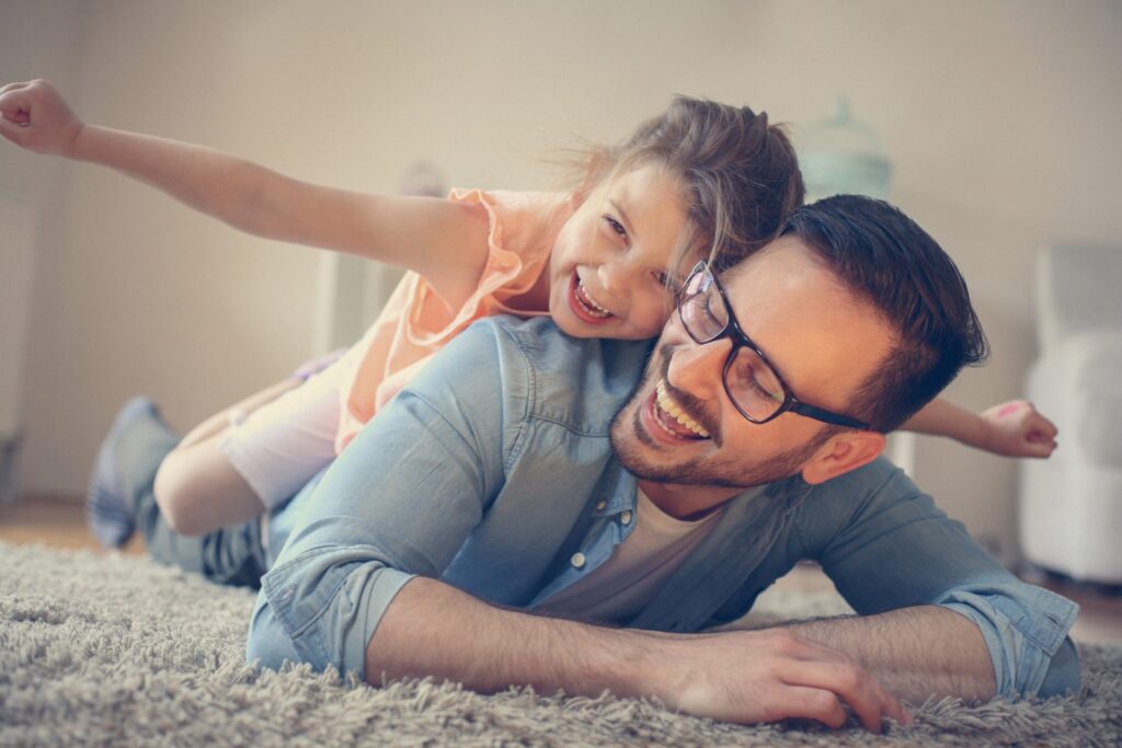 A father and daughter playing together as he thinks about the total cost of solar panels and what an investment it will be for their future.