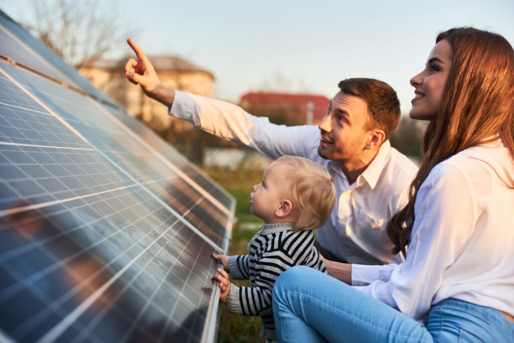 A woman in solar with her family looking at a solar panel.